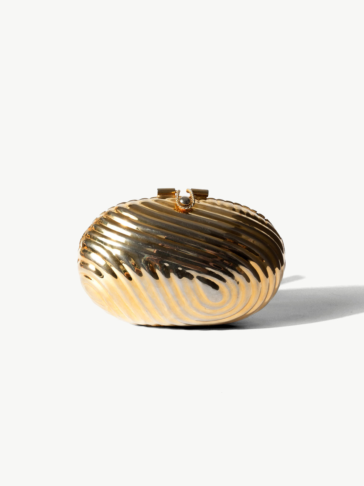 A gold metallic oval clutch bag with a ribbed, wavy striped pattern and a small top clasp, photographed on a clean white background with a soft shadow.